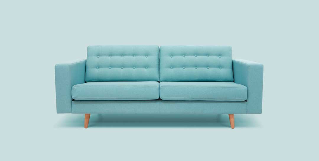 Das Bild zeigt ein modernes, hellblaues Zweisitzer-Sofa mit einem schlichten, minimalistischen Design auf einem passenden hellblauen Hintergrund. Das Sofa hat eine geknöpfte Rückenlehne mit einem symmetrischen Muster aus kleinen Knöpfen, breite Armlehnen und steht auf schlanken, hölzernen Beinen in einem natürlichen Holzton. Die klare Linienführung und die helle türkisblaue Farbe verleihen dem Möbelstück eine frische, zeitgenössische Ausstrahlung, die Ruhe und Entspannung vermittelt.